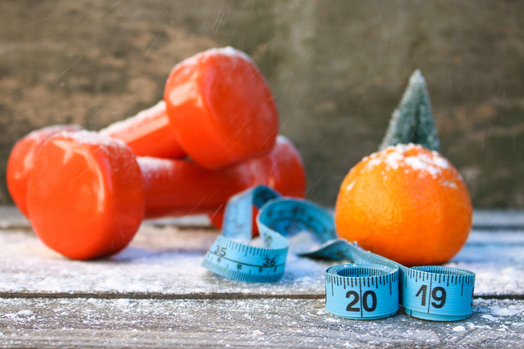 Hand weights, tape measure and fresh orange as reminder to take care of our bodies as we age.