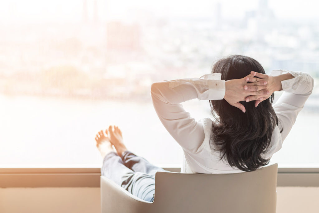 Woman over 50 gazing out of office window 